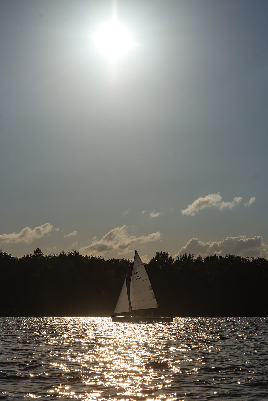 Sailboat Silhouette on Sparkling Lake at Sunset