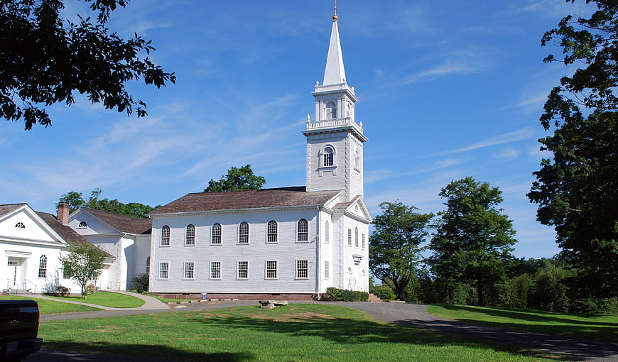 White colonial church with steeple on sunny day