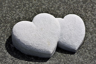 Two White Stone Hearts on Gray Granite Surface