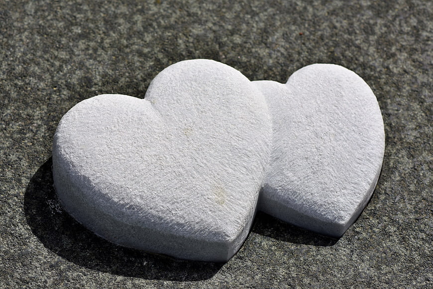 Two White Stone Hearts on Gray Granite Surface