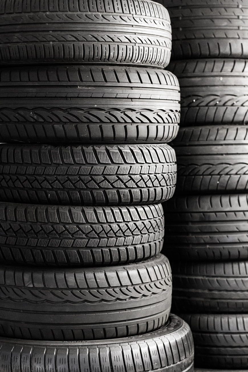 Stack of black car tires with detailed tread patterns