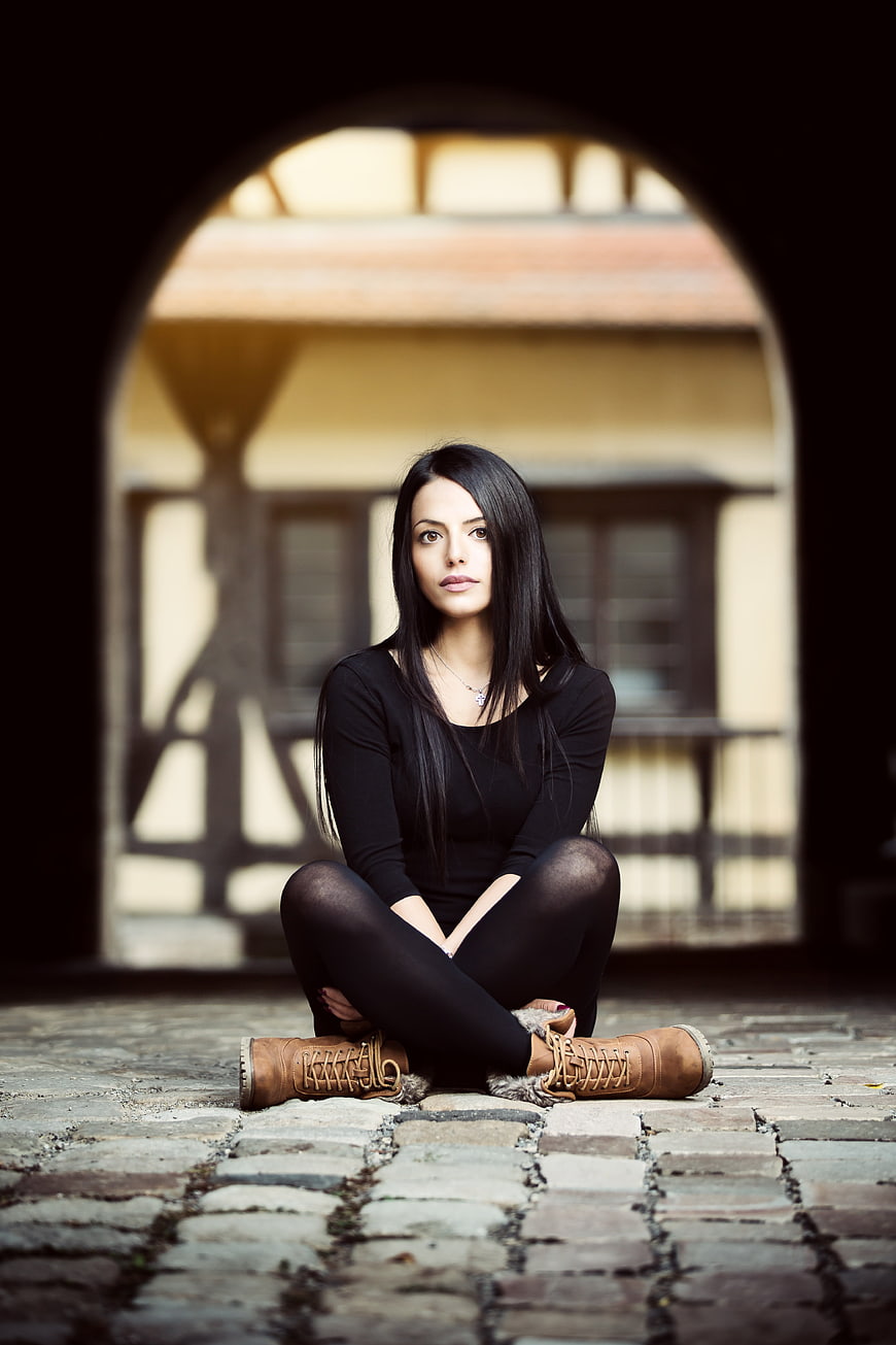 Woman in Black Sitting in Arched Courtyard
