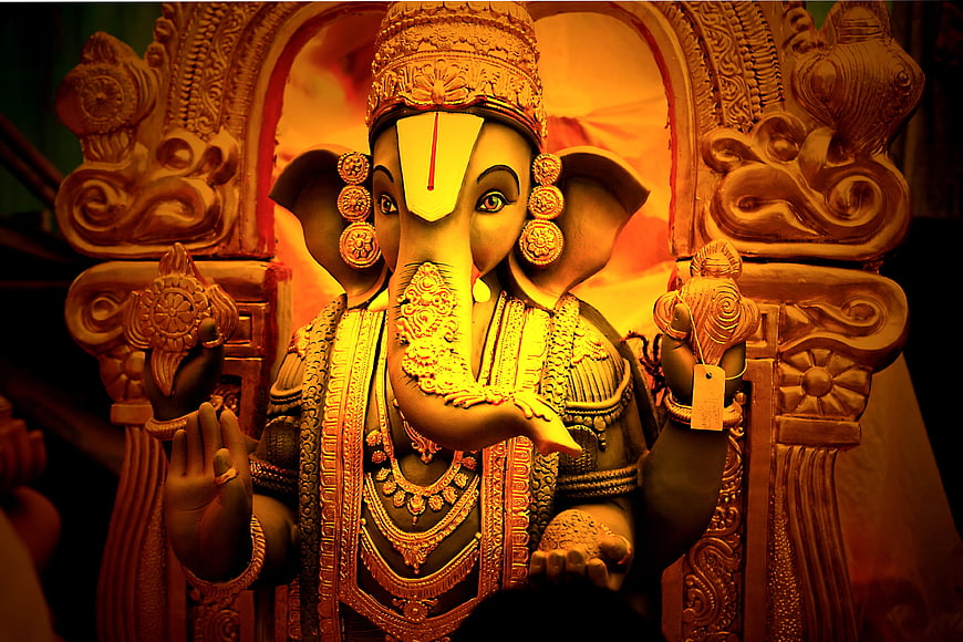 Ornate Ganesha Statue Illuminated By Warm Golden Temple Light