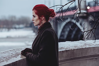 Red-haired woman in winter coat looking away