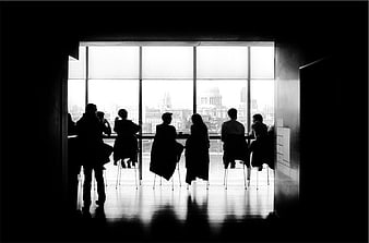 Silhouetted Group Meeting at Large Window with City View