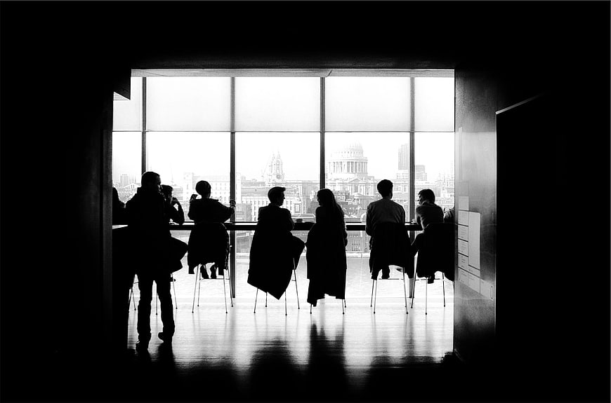Silhouetted Group Meeting at Large Window with City View