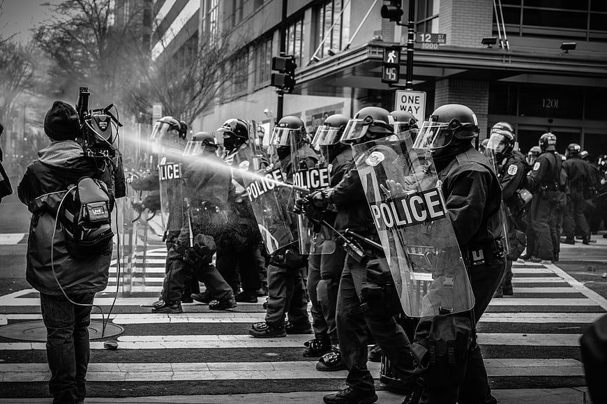Black and white photo of riot police line facing a cameraman
