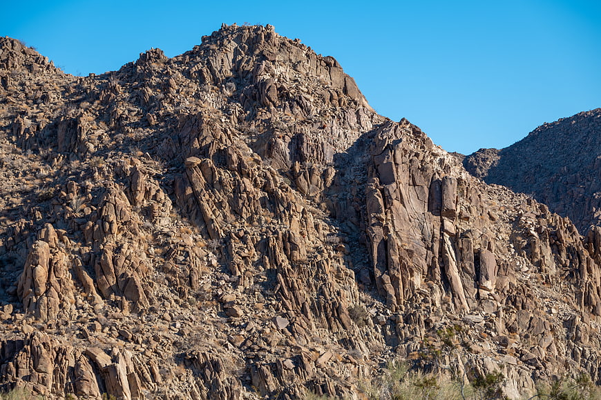Rugged desert mountain peak with rocky texture and blue sky
