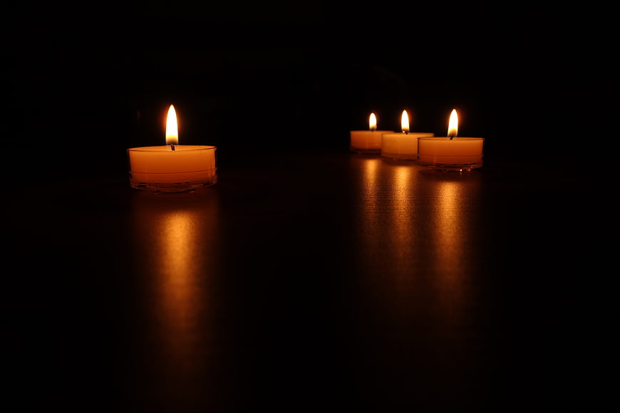 Tea light candles glowing on dark reflective surface
