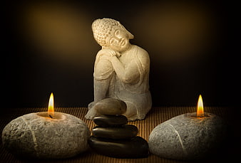 Zen Buddha Statue with Candles and Stacked Stones