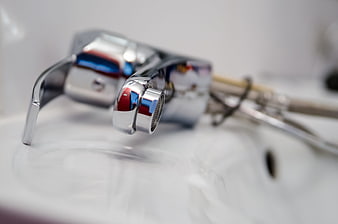 Close-up of chrome faucet with plumbing tools on white sink