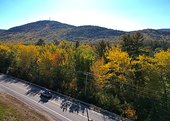 Car driving on rural road through autumn mountain landscape