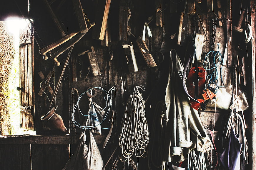 Rustic wooden shed interior with hanging tools and ropes