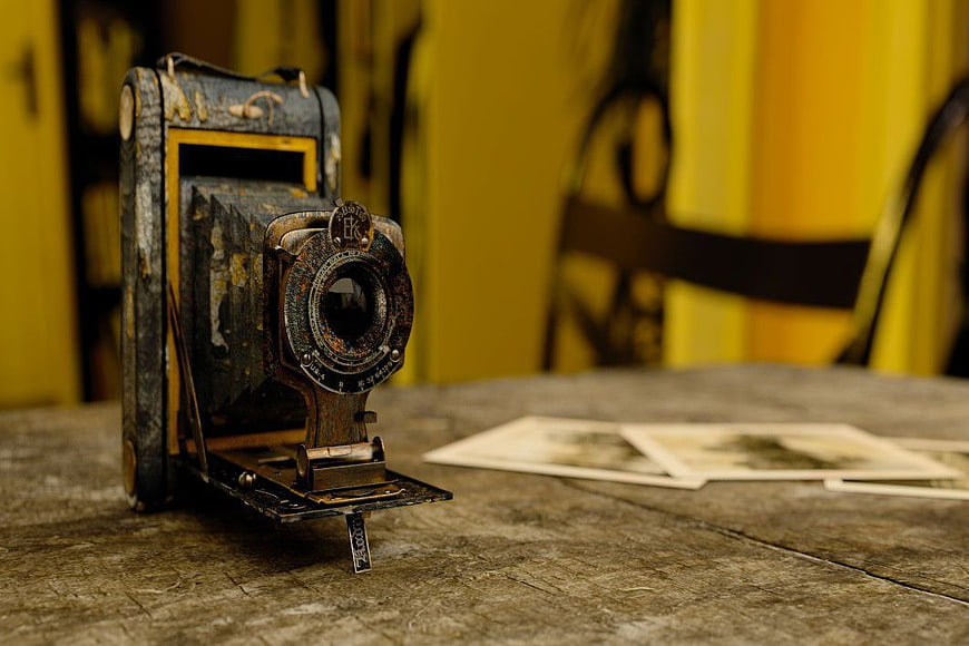 Vintage rusty camera on wooden table with old photos