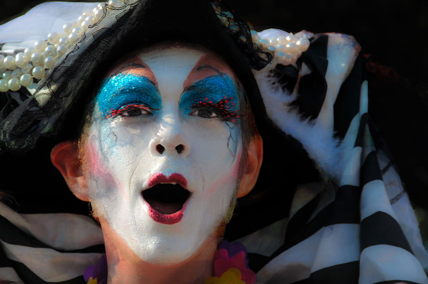 Close-up of a performer with white face paint and blue glittery eye makeup