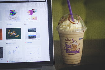 Iced coffee drink next to laptop screen displaying design portfolio