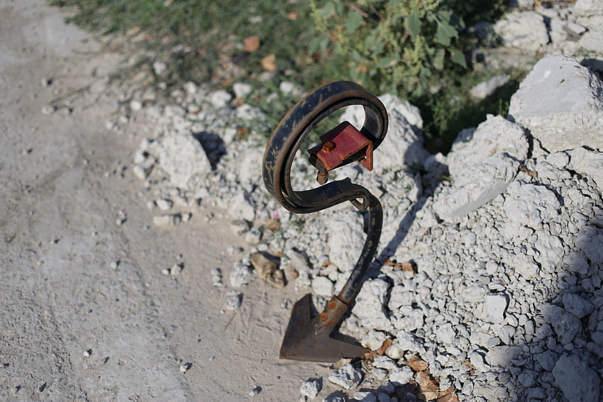 Rusty vintage plow cultivator on rocky ground