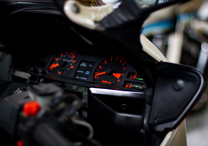 Close-up of motorcycle dashboard with orange speedometer