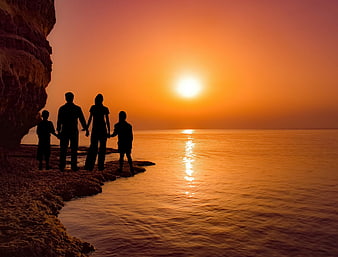 Family Silhouette Watching Sunset Over Calm Sea