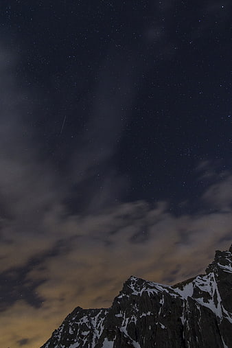 Snowy Mountain Peak Under Starry Night Sky with Clouds