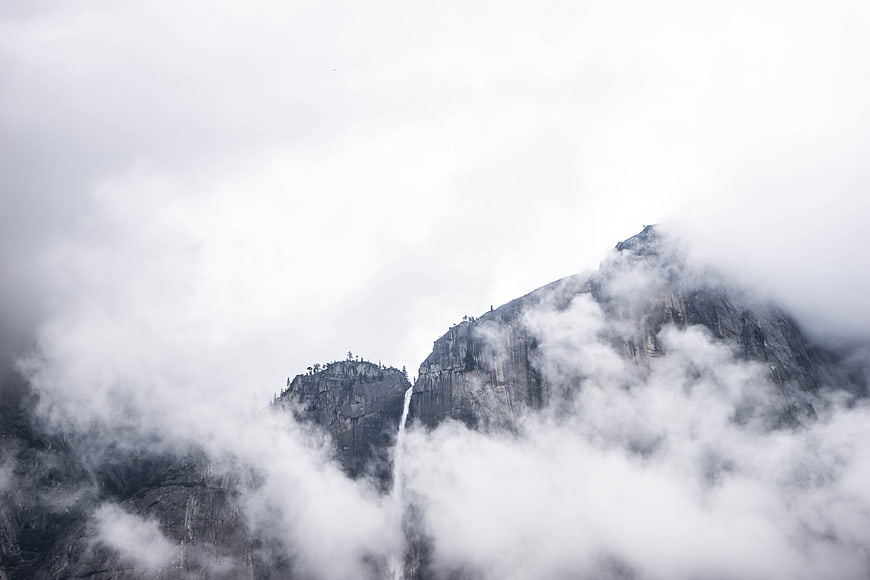 Misty Mountain Peaks with Waterfall Through Clouds