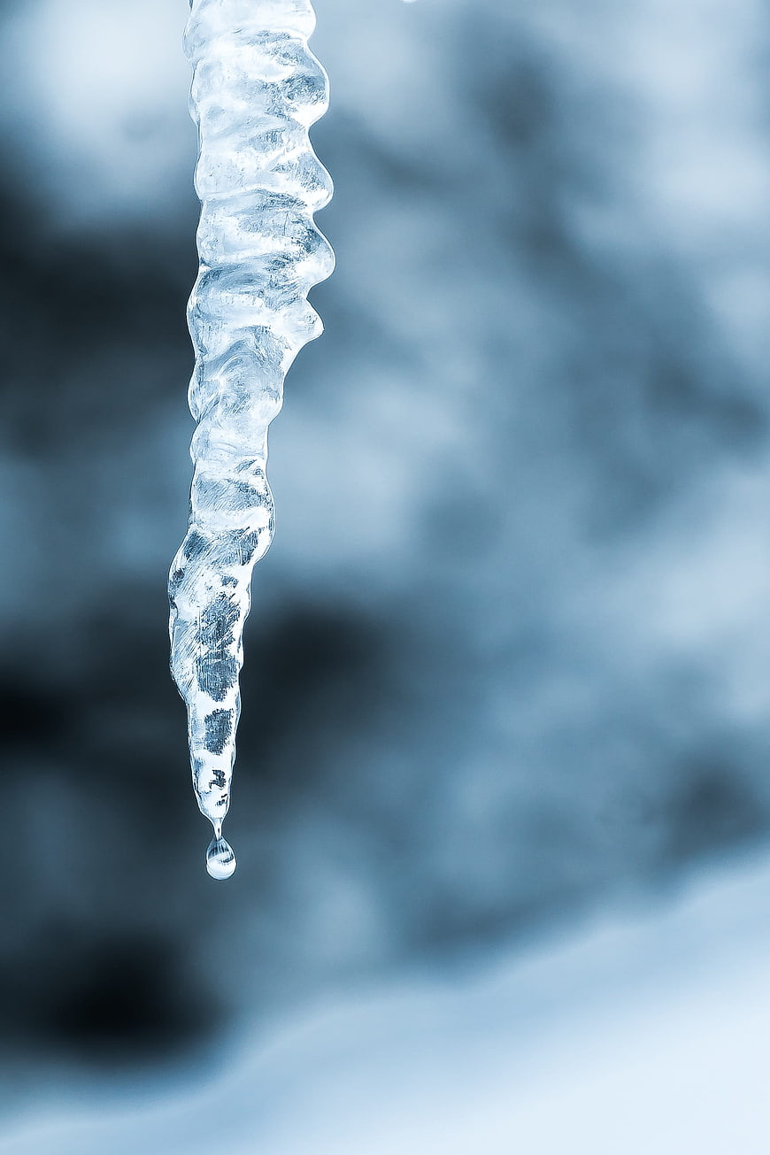 Close-up of a melting icicle with a water droplet