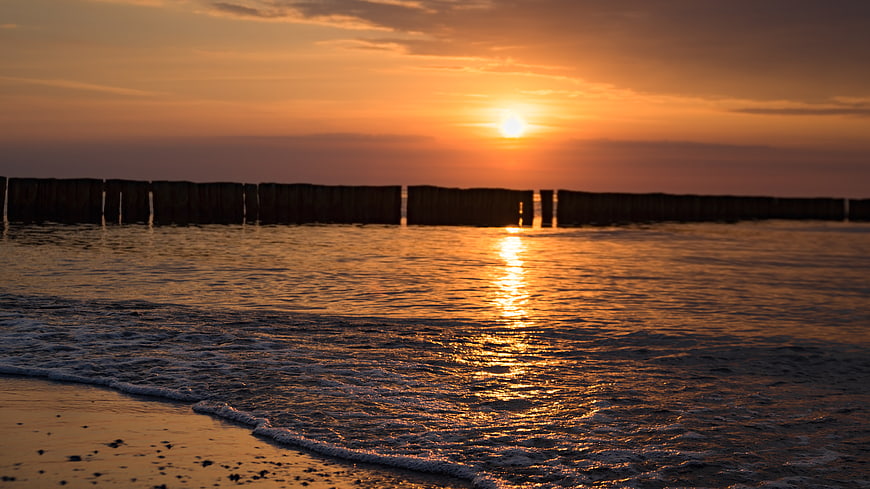 Golden sunset over Baltic Sea with wooden groynes