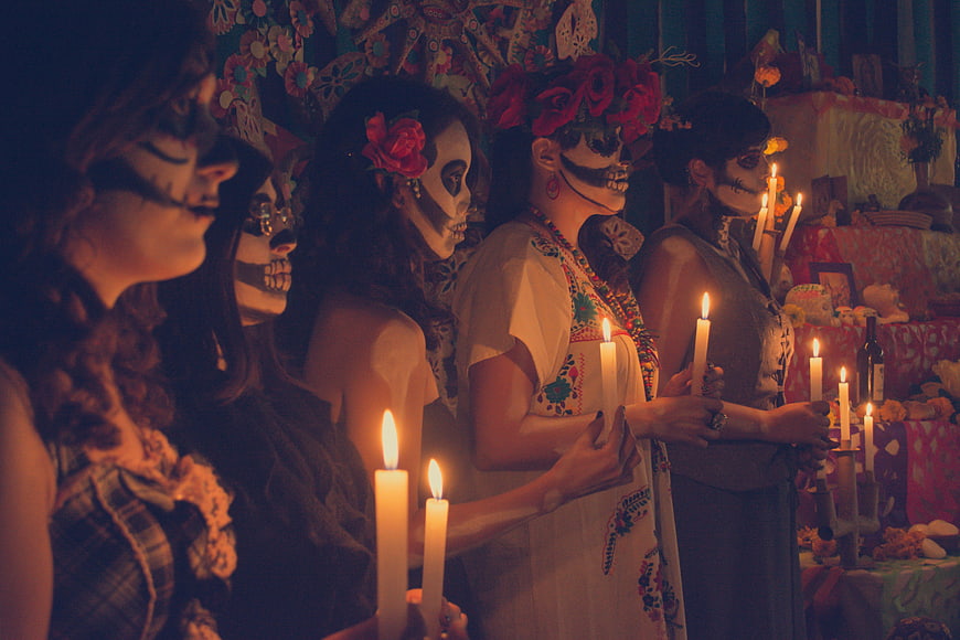 Women with Sugar Skull Makeup Holding Candles at Day of the Dead Altar