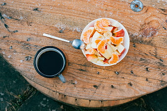 Top view of fresh fruit salad and black coffee on rustic wooden barrel