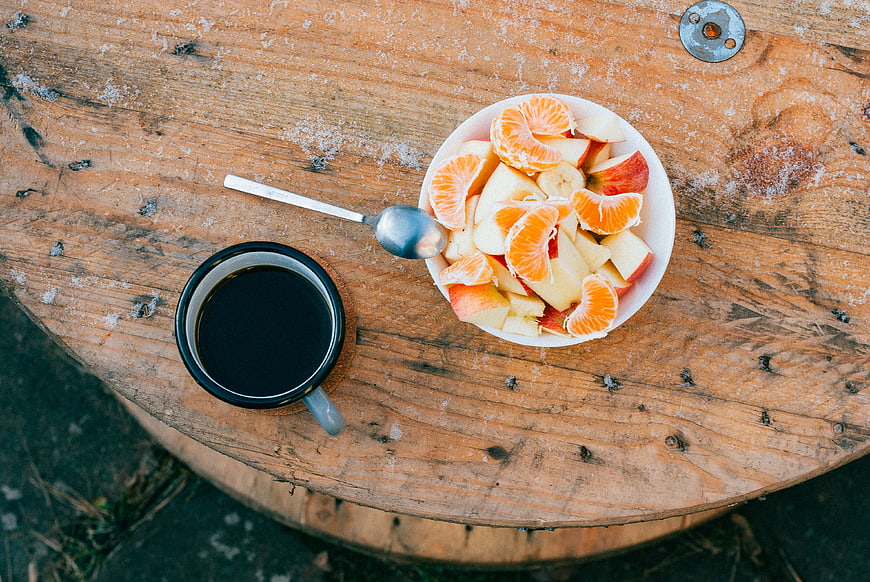 Top view of fresh fruit salad and black coffee on rustic wooden barrel