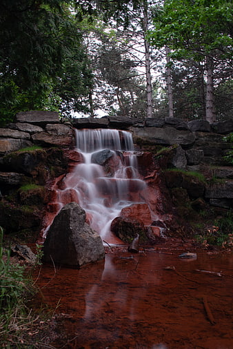 Small waterfall cascading over red rocks in a forest