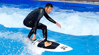 Man surfing on artificial wave pool in wetsuit