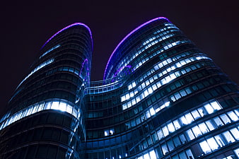 Modern Curved Glass Office Building at Night with Blue Neon Lights