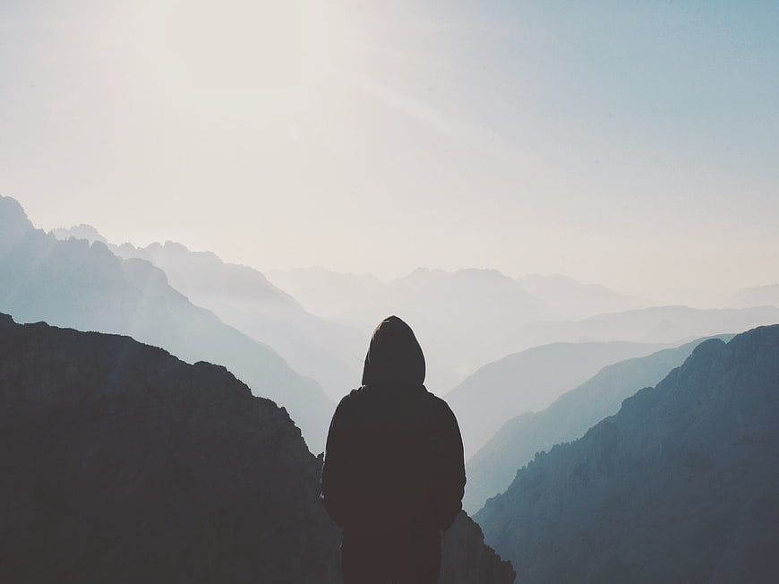 Silhouette of Hiker Looking at Misty Mountain Range