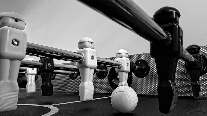 Close-up of black and white foosball table players and ball
