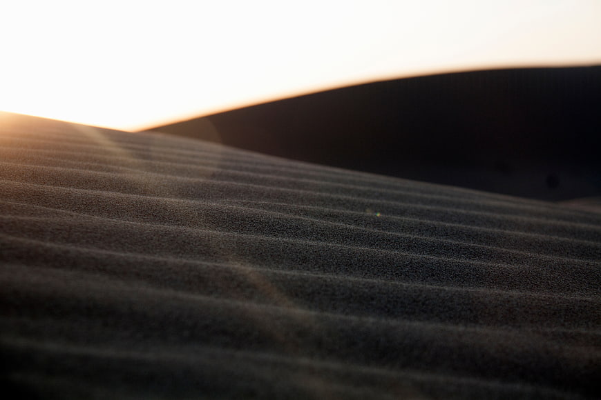 Rippled sand dunes at sunset with golden light