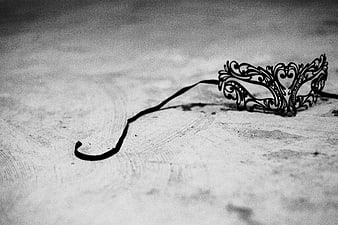 Black ornate masquerade mask on textured white surface