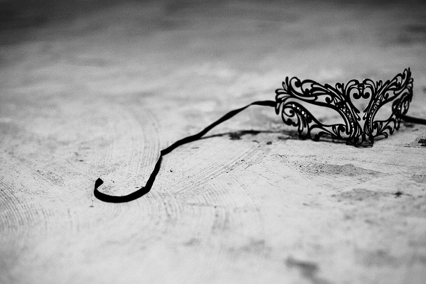Black ornate masquerade mask on textured white surface