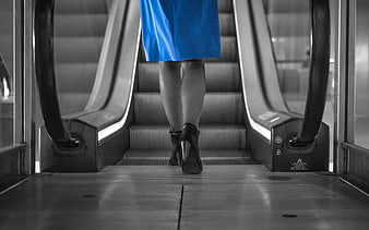 Woman in Blue Dress Walking Up Escalator