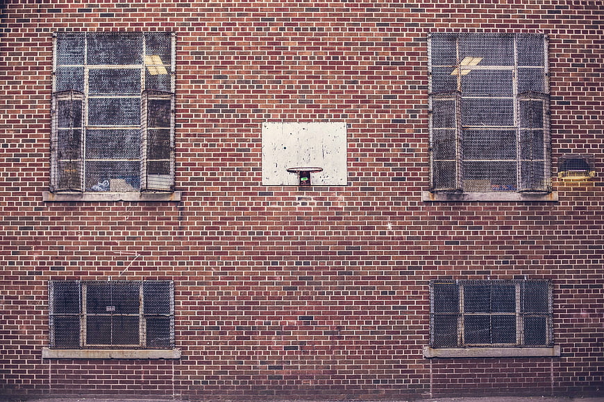Miniature basketball hoop mounted on red brick wall
