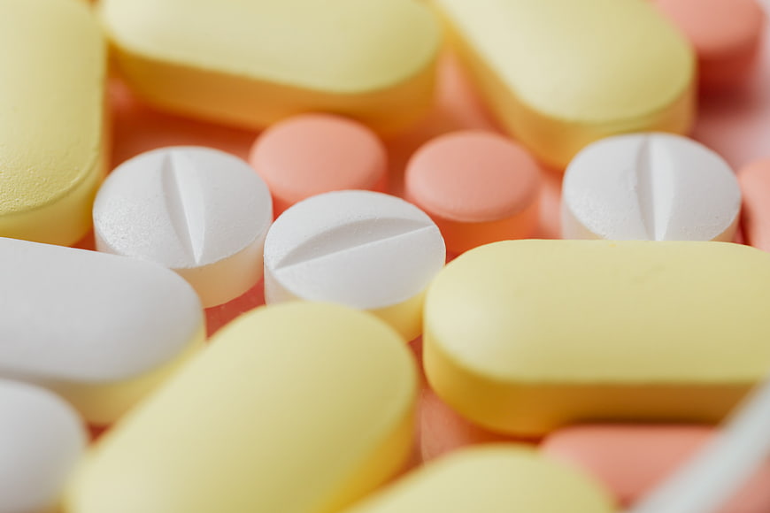 Close-up of assorted yellow, white, and pink pills