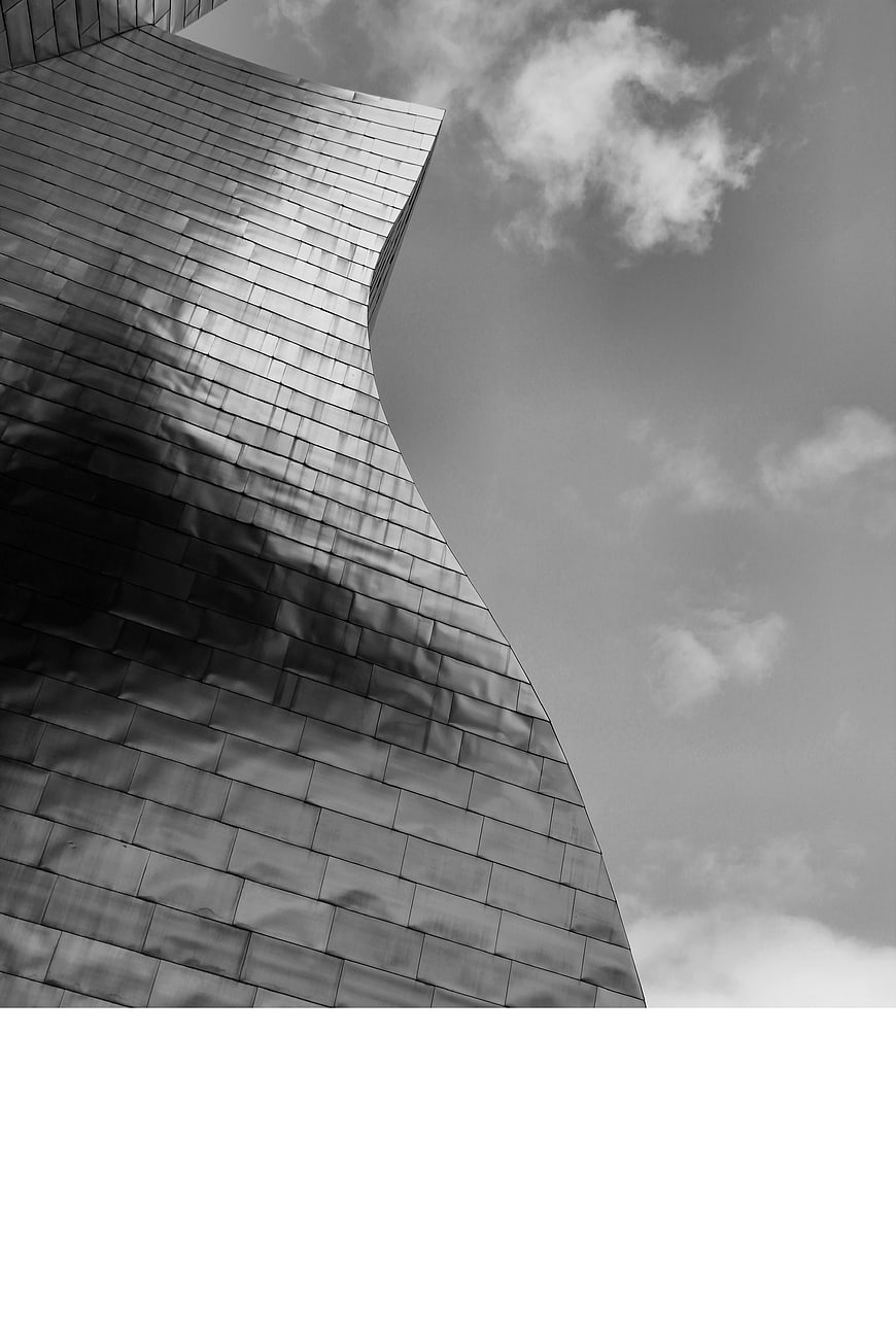 Black and white modern curved metal architecture against cloudy sky