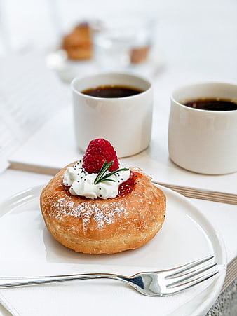 Raspberry cream donut with coffee on white table