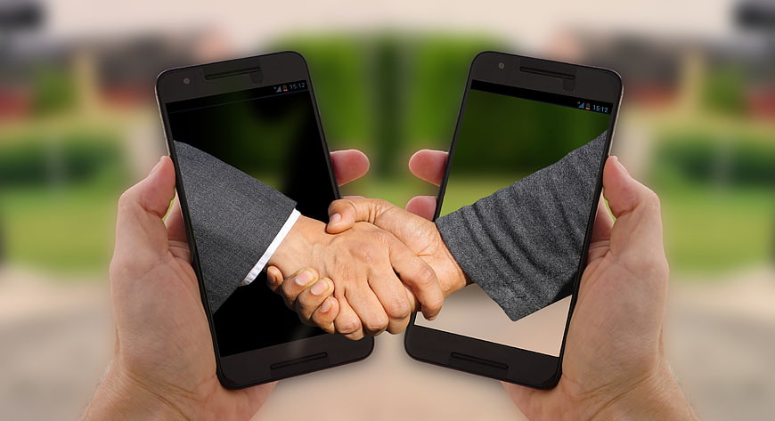 Smartphones displaying handshake for digital business agreement