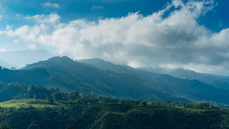 Majestic Green Hills and Mountains Under Blue Sky