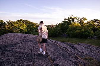 Man hiking on rocky outcrop at sunset