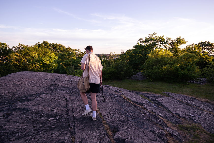 Man hiking on rocky outcrop at sunset