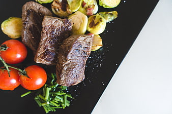 Grilled Beef Steak with Brussels Sprouts and Tomatoes on Black Plate