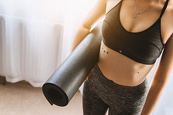 Woman holding yoga mat in athletic wear