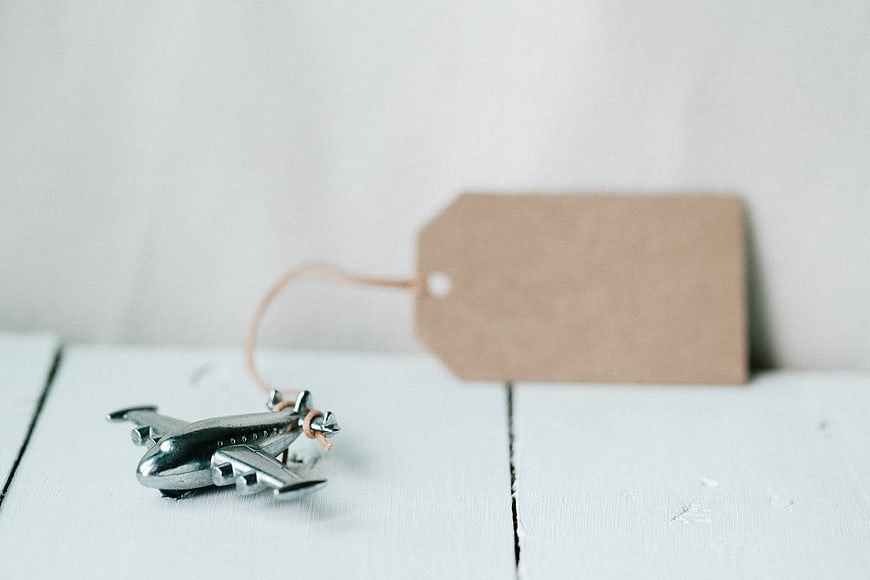 Silver toy airplane with blank tag on white wood